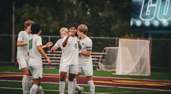 The boys soccer team celebrates after a goal.