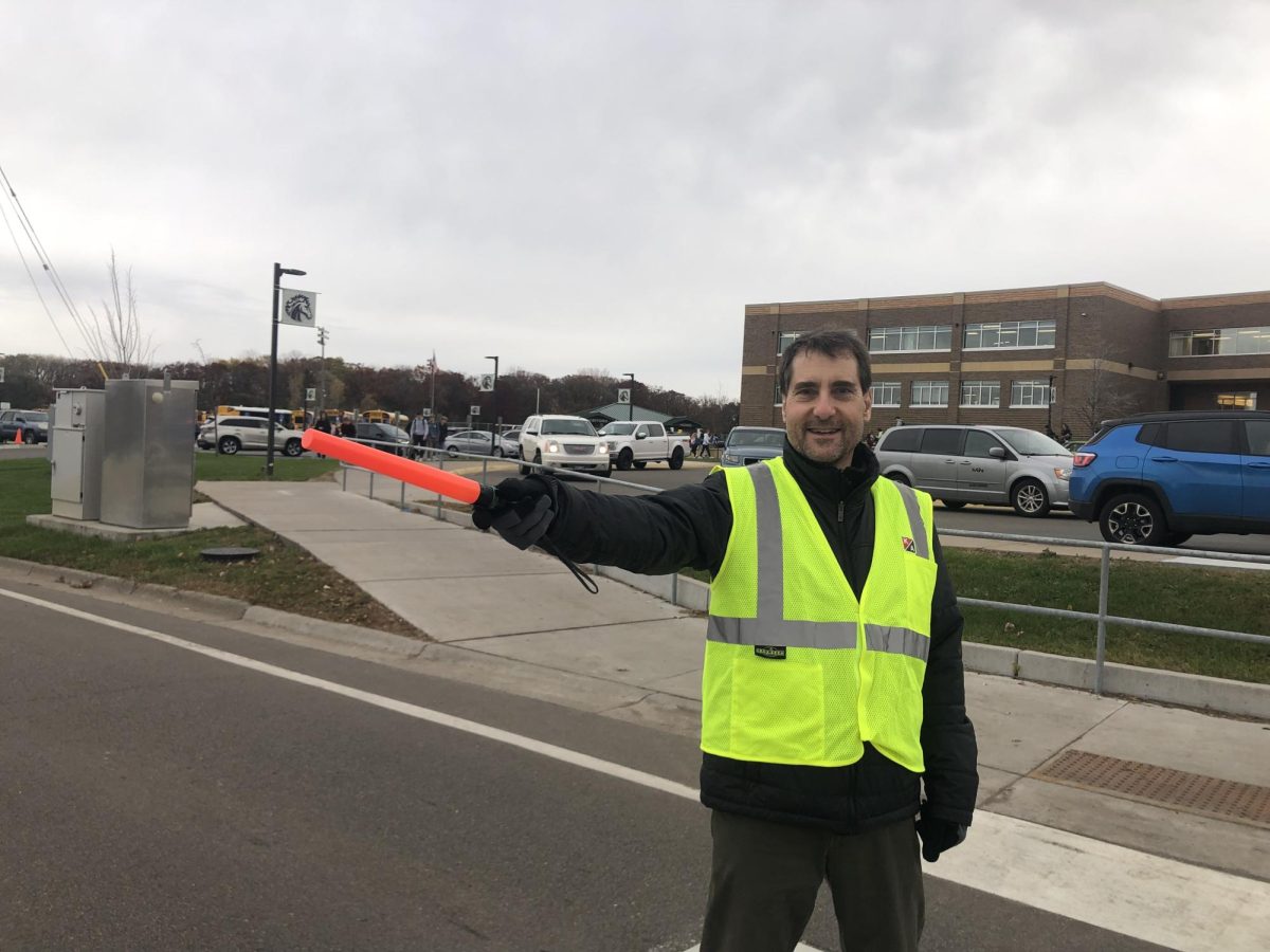 Paul Cicmil directs traffic near the entrance to the north parking lot, chatting with students as they cross the nearby crosswalk.