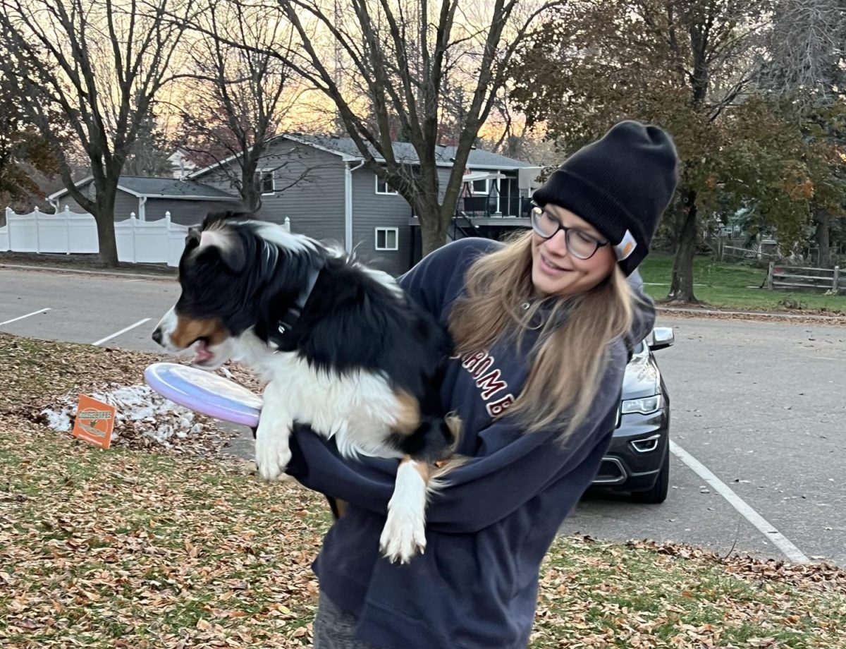 Grimm holds Parker, her service dog, as he goes for the disc.