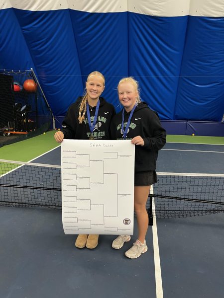 Senior Rory Wahlstrand and sophomore holding up their section tournament doubles bracket after winning in the final.